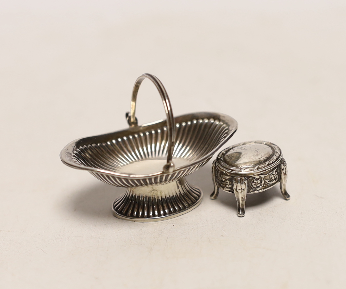 An Edwardian miniature silver model of a basket, by Levi & Salaman, Birmingham, 1907, 56mm, together with a miniature silver model of a table, import marks for London, 1901.